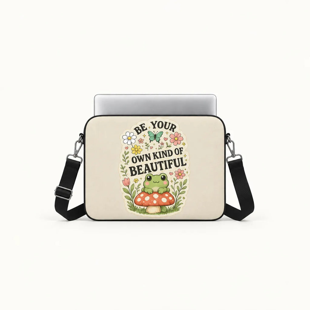 Cute green frog sitting on a red toadstool surrounded by flowers and Be Your Own Kind of Beautiful typography on cream padded laptop sleeve by SLEEVER