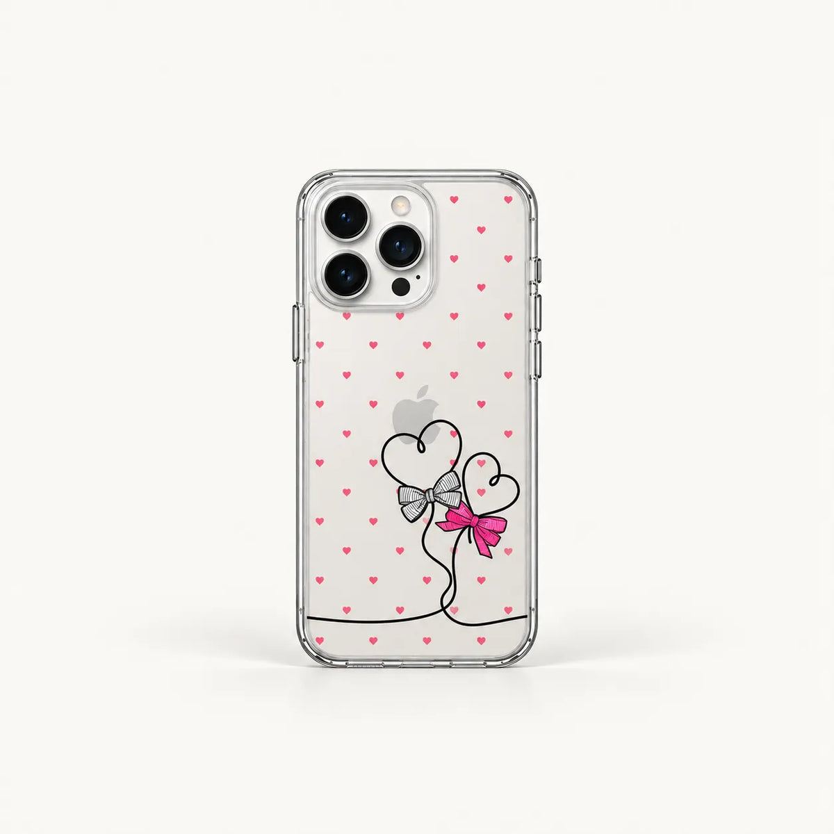 A clear protective phone case for an iPhone, decorated with a pattern of small pink hearts and a central graphic of two heart balloons tied with a pink bow and silver ribbon.