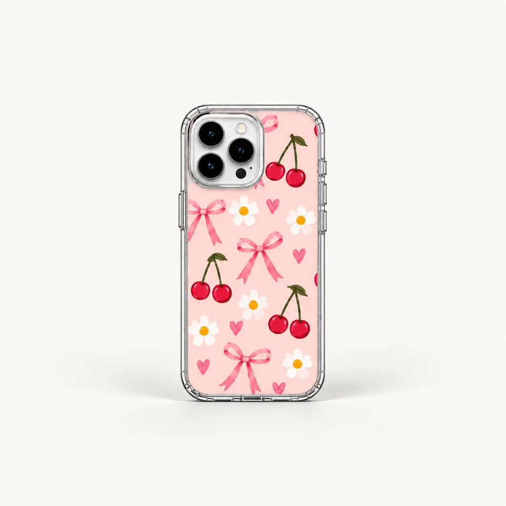 A clear-sided phone case with a light pink back decorated with a repeating pattern of red cherries, pink bows, small pink hearts, and white daisies, shown on a white background.