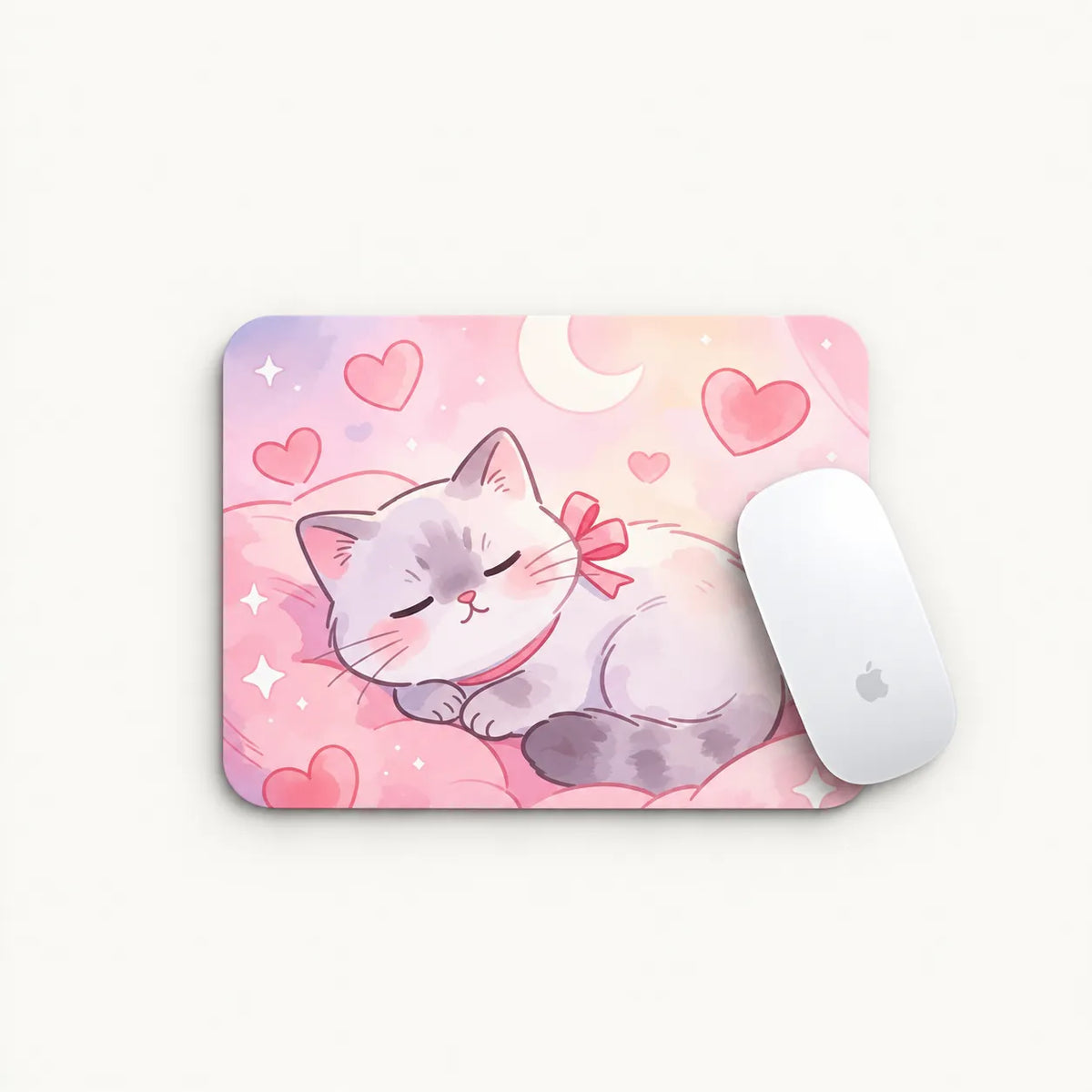 A rectangular mouse pad with a pastel illustration of a sleeping gray cat wearing a pink bow, surrounded by pink hearts and a crescent moon on a pink background. A white computer mouse rests on the right side of the pad against a light off-white background.