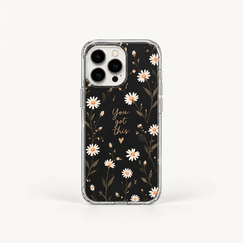 A clear phone case with a black floral print featuring white daisies, gold leaves, and the phrase 'You are this' in gold script, shown on a light gray background.