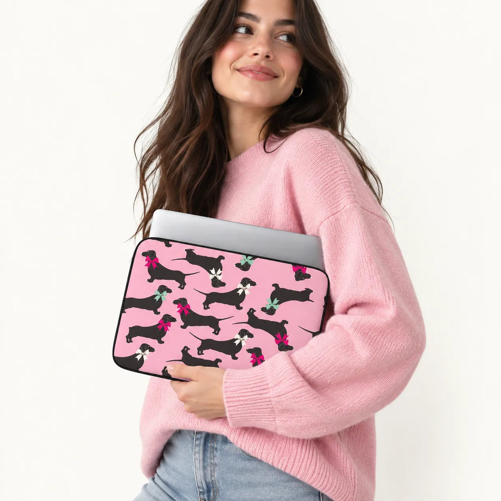 Seamless pattern of black dachshund dogs wearing colorful pink white and green ribbons on a pink padded laptop sleeve by SLEEVER