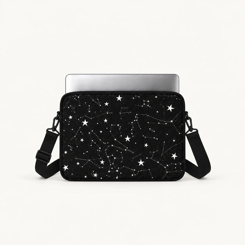 A black laptop sleeve featuring a white star and constellation pattern, shown with a silver laptop inserted and a black shoulder strap against a clean white background.