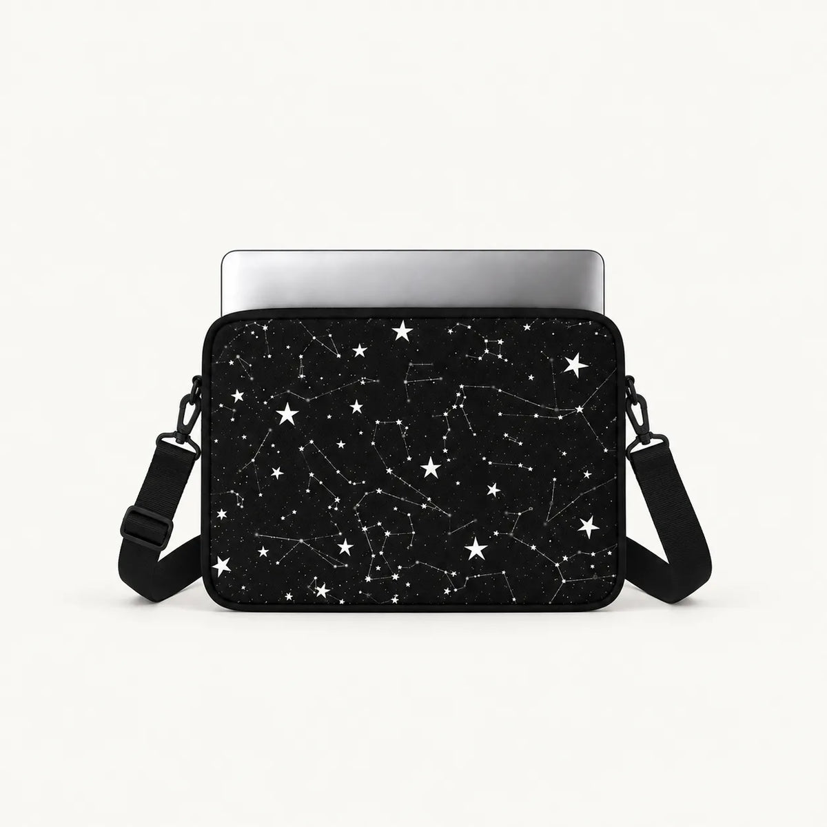 A black laptop sleeve featuring a white star and constellation pattern, shown with a silver laptop inserted and a black shoulder strap against a clean white background.