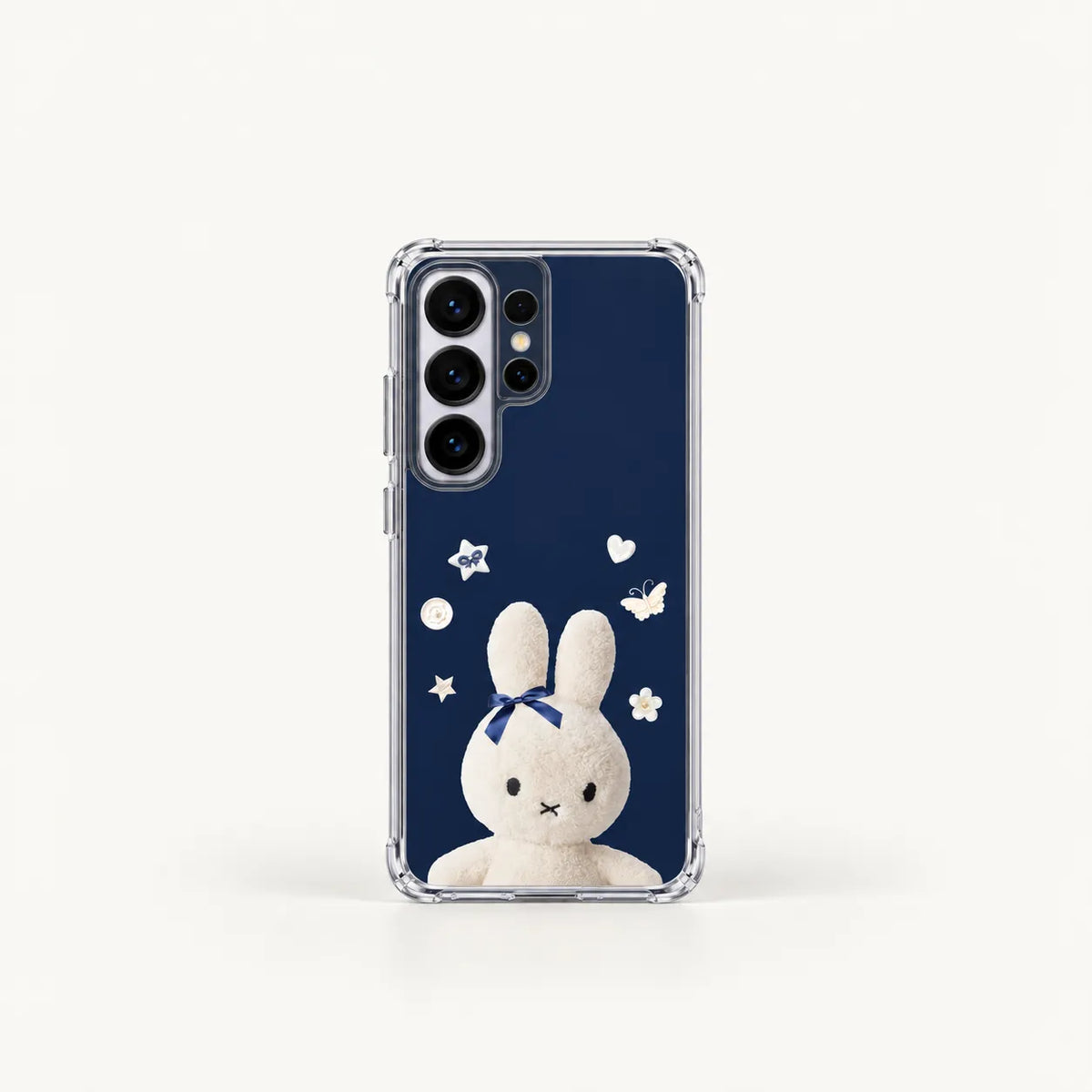 A clear phone case featuring a navy blue back print with a white bunny wearing a blue bow, surrounded by small white stars and hearts, shown on a light gray background.