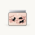 Three black cats playing among Japanese cherry blossom sakura branches on a pastel pink padded laptop sleeve by SLEEVER
