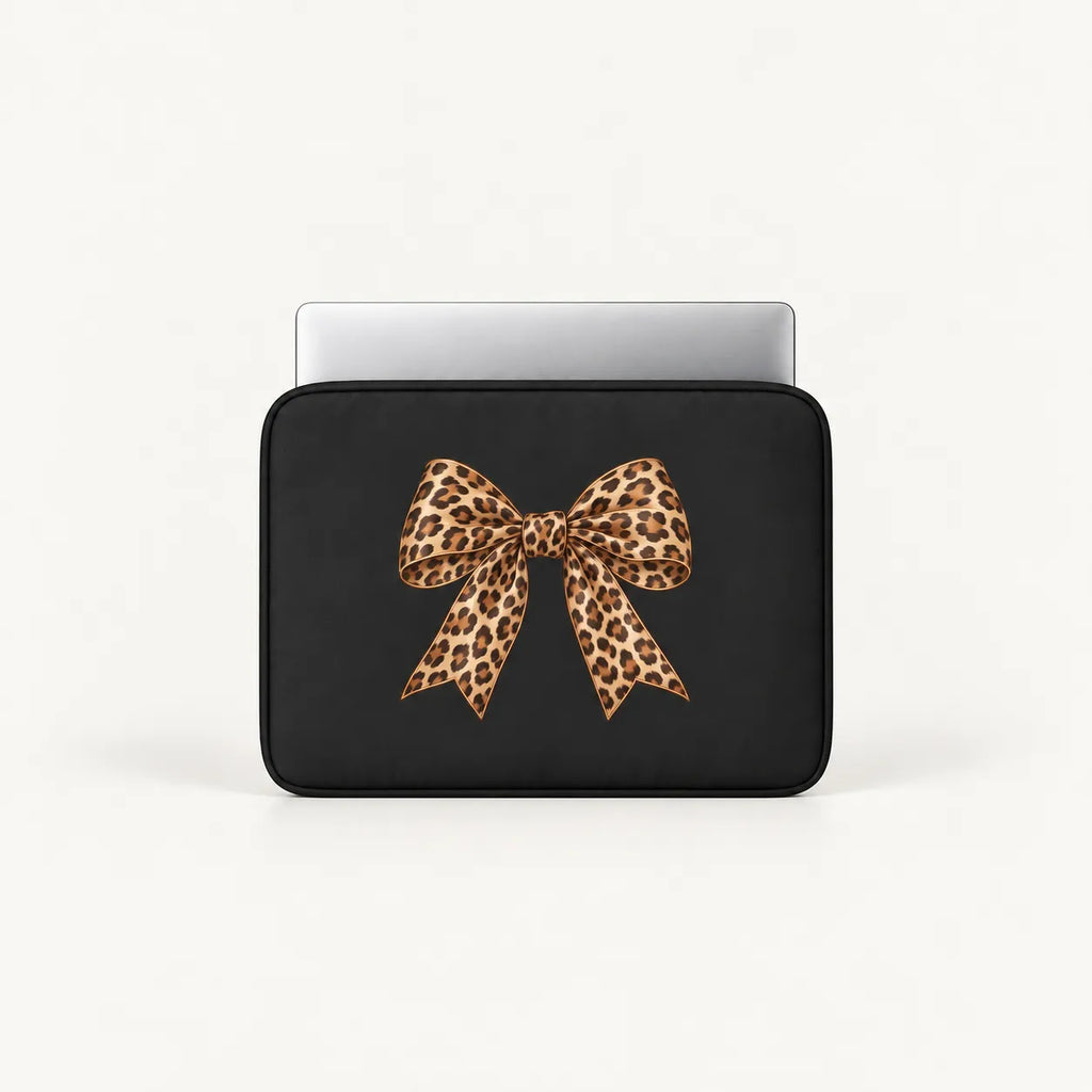 A black laptop sleeve with a large leopard-print bow graphic on the front, shown with a silver laptop partially inserted, against a clean white background.