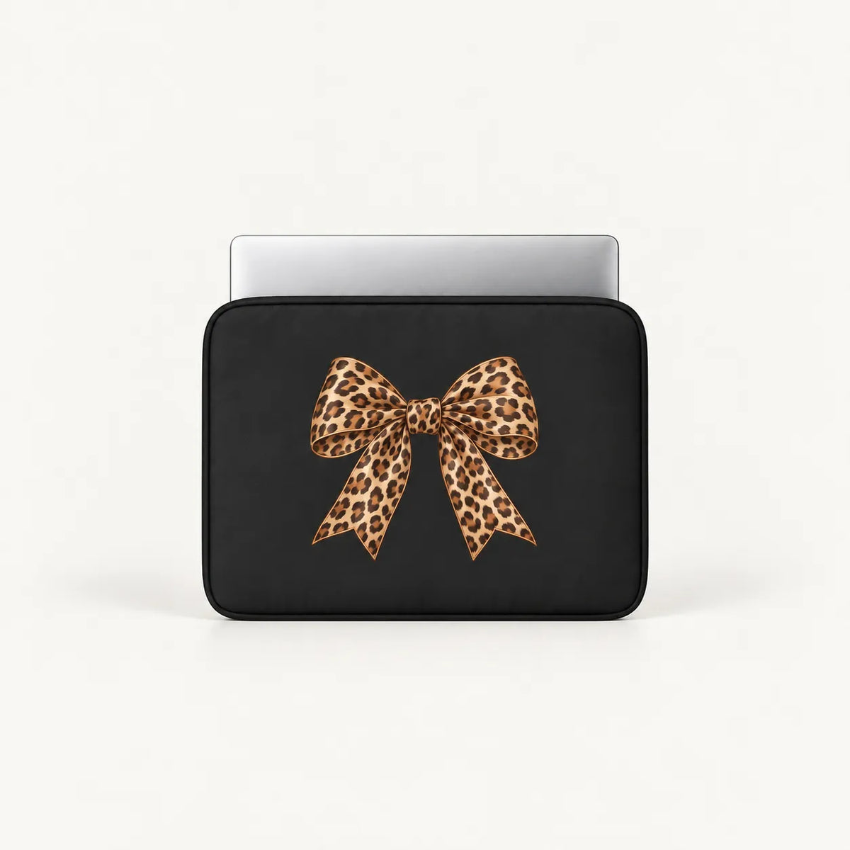 A black laptop sleeve with a large leopard-print bow graphic on the front, shown with a silver laptop partially inserted, against a clean white background.