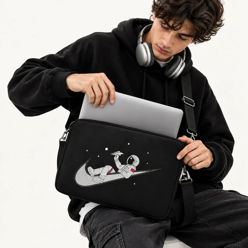 Illustration of an astronaut relaxing on a swoosh logo holding a paper plane in space on a black padded laptop sleeve by SLEEVER