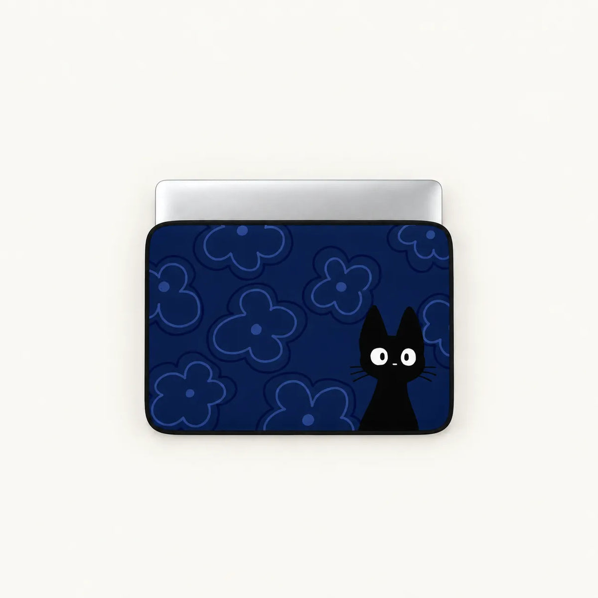 A laptop sleeve featuring a dark blue background with light blue floral outlines and a black cat character peeking from the right side, shown on a silver laptop against a light off-white background.