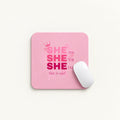 A pink rectangular mouse pad with rounded corners featuring the text 'SHE can SHE Will SHE Did She is me!' in pink and magenta lettering, shown on a light background with a white computer mouse resting on it.