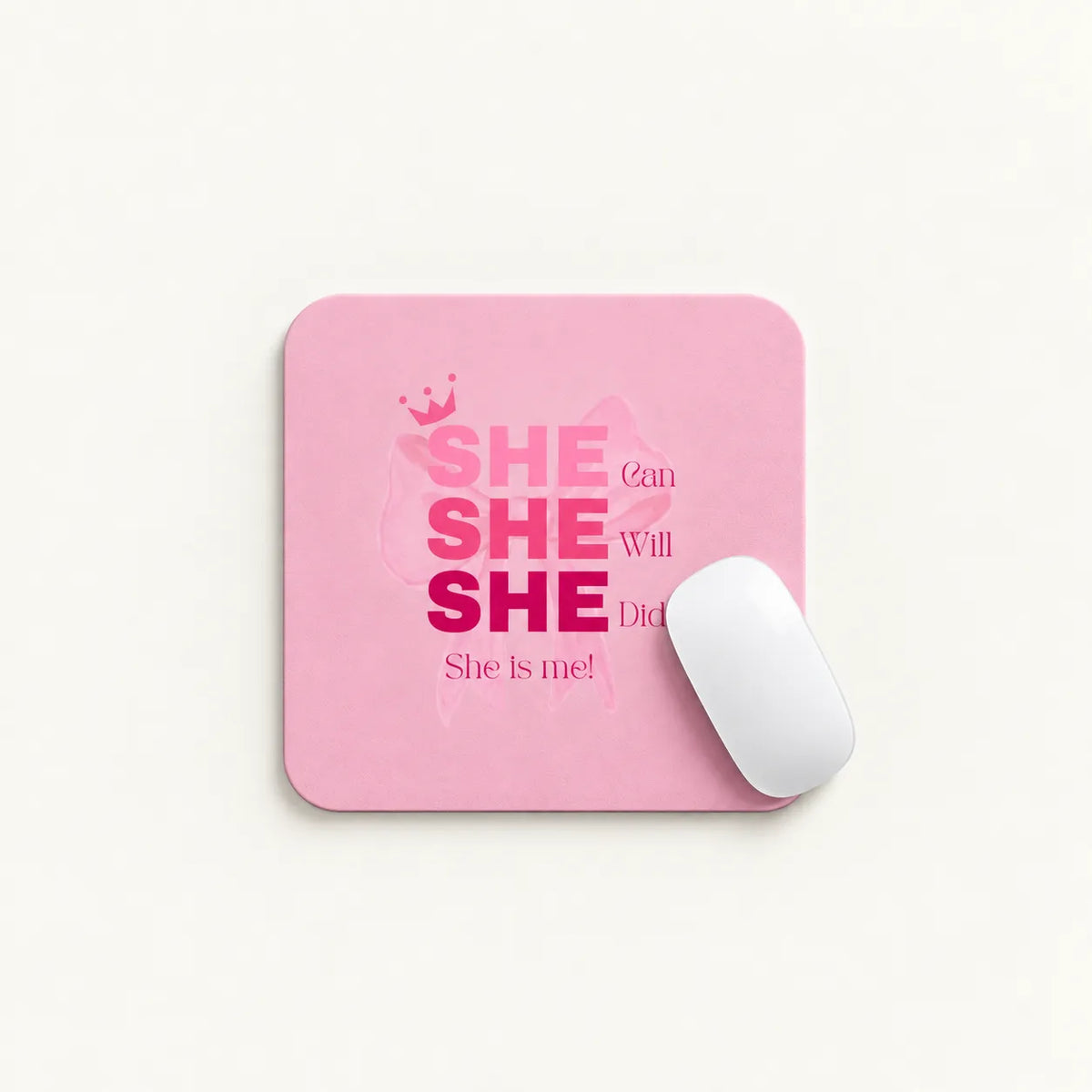A pink rectangular mouse pad with rounded corners featuring the text 'SHE can SHE Will SHE Did She is me!' in pink and magenta lettering, shown on a light background with a white computer mouse resting on it.