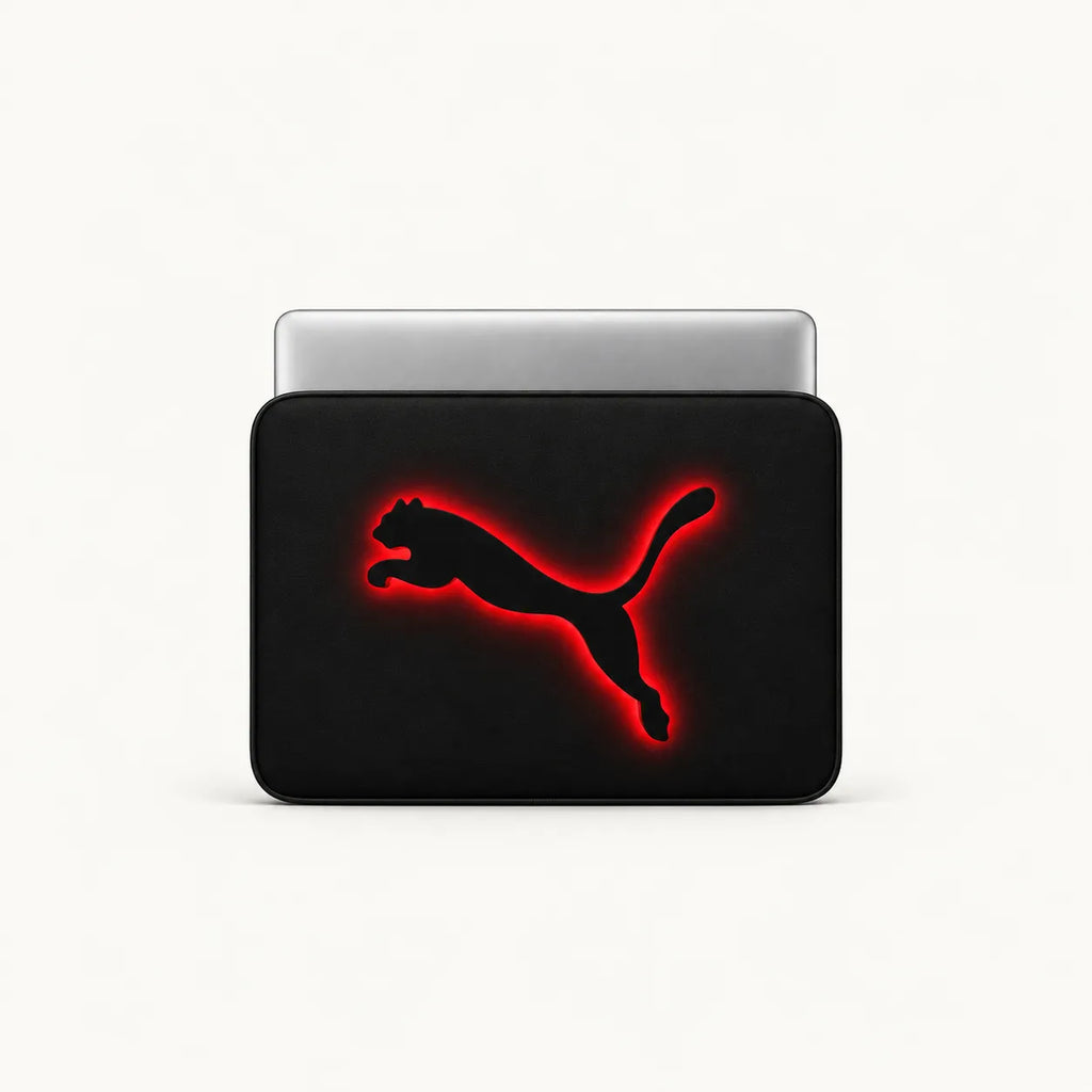 A black laptop sleeve featuring the Puma leaping cat logo in black with a glowing red outline, shown with a silver laptop partially inserted, on a clean white background.