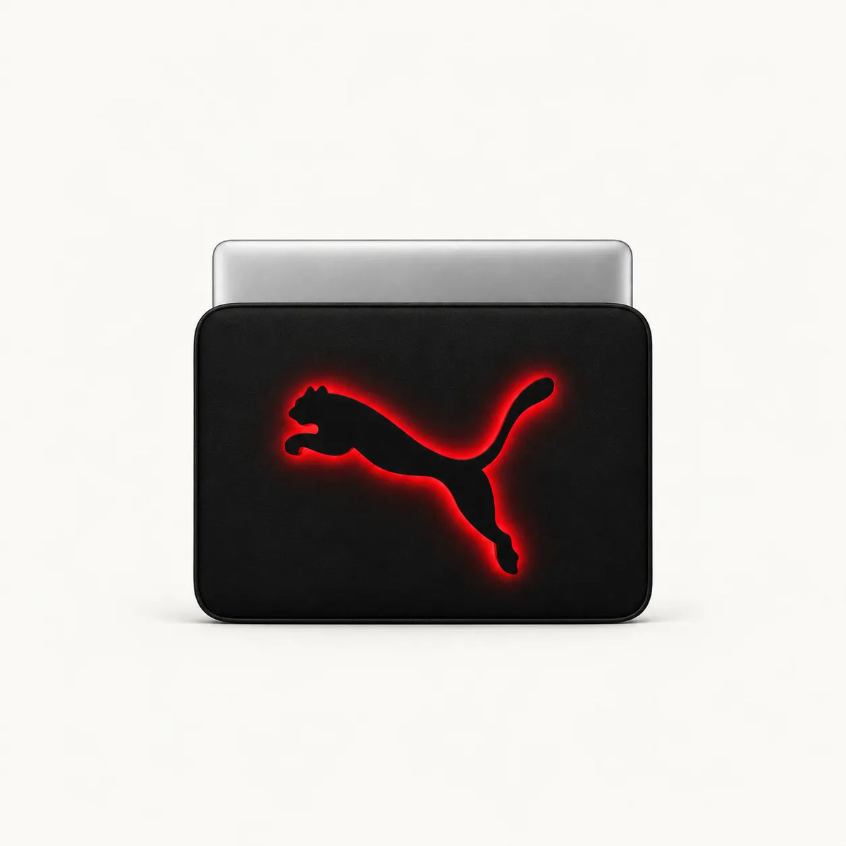 A black laptop sleeve featuring the Puma leaping cat logo in black with a glowing red outline, shown with a silver laptop partially inserted, on a clean white background.