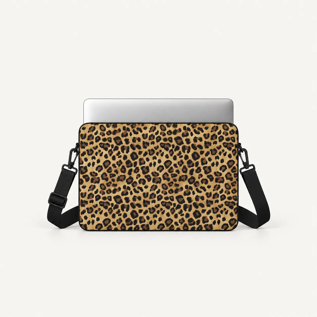 A laptop sleeve with a tan and black leopard print pattern, shown with a silver laptop inserted and a black shoulder strap against a light gray background.