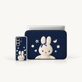 A navy blue laptop sleeve with a white bunny illustration is shown next to a matching smartphone case, both on a clean white background.