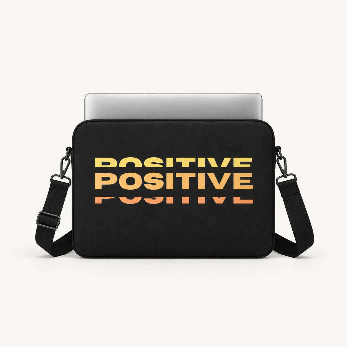 Repeated stacked POSITIVE typography in warm yellow orange sunset gradient effect on a black padded laptop sleeve by SLEEVER