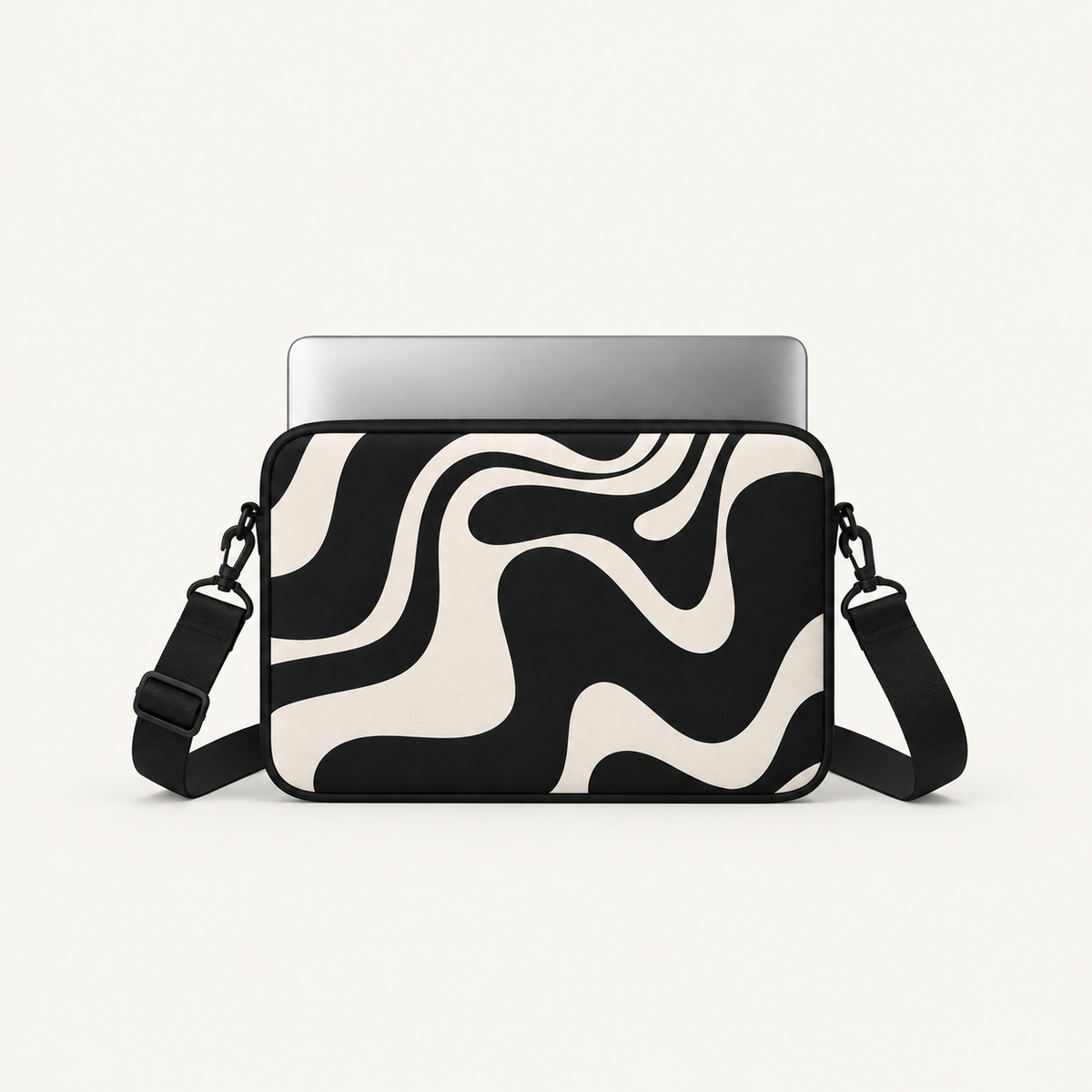 A black and cream wavy abstract patterned laptop sleeve with an adjustable shoulder strap, shown holding a silver laptop against a light off-white background.