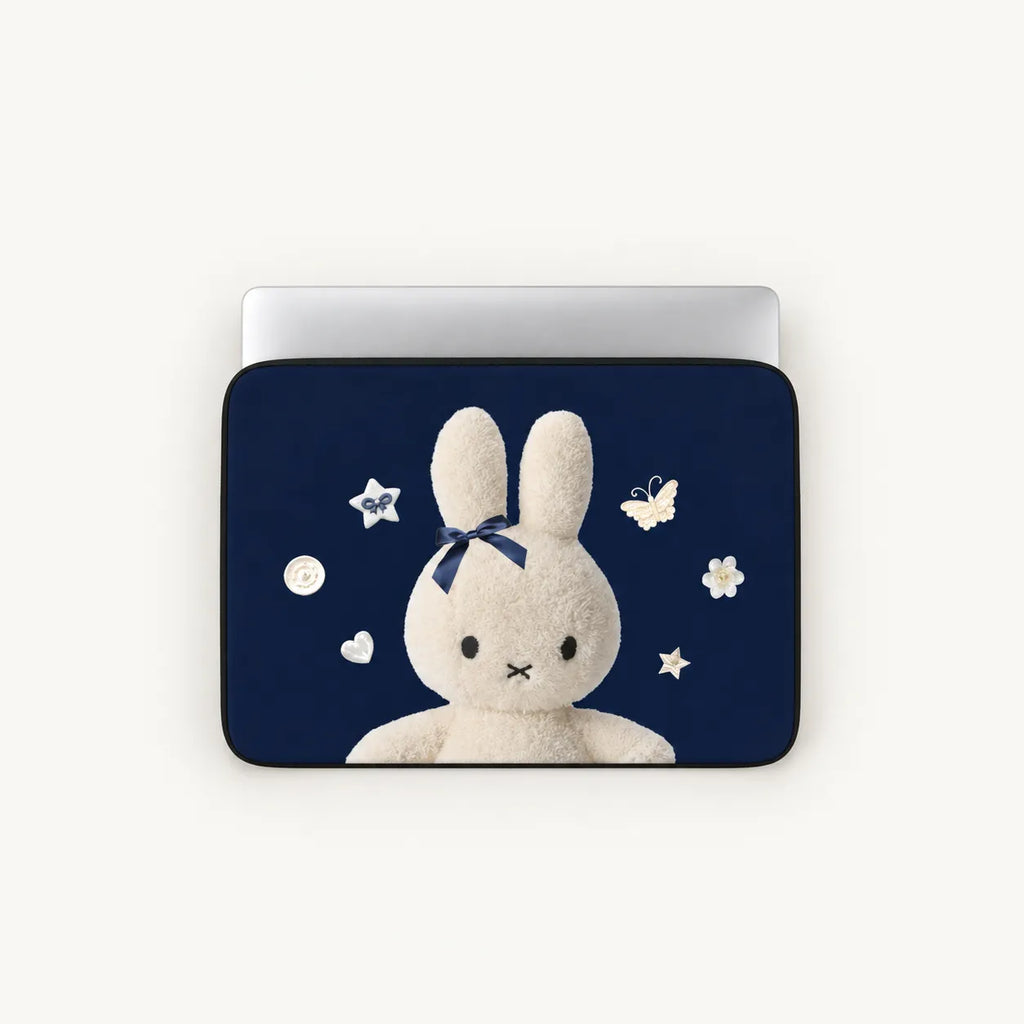 A laptop sleeve featuring a navy blue background with a white plush bunny wearing a dark blue bow, surrounded by small white stars, flowers, and butterflies. The sleeve is shown on a silver laptop against a light off-white background.