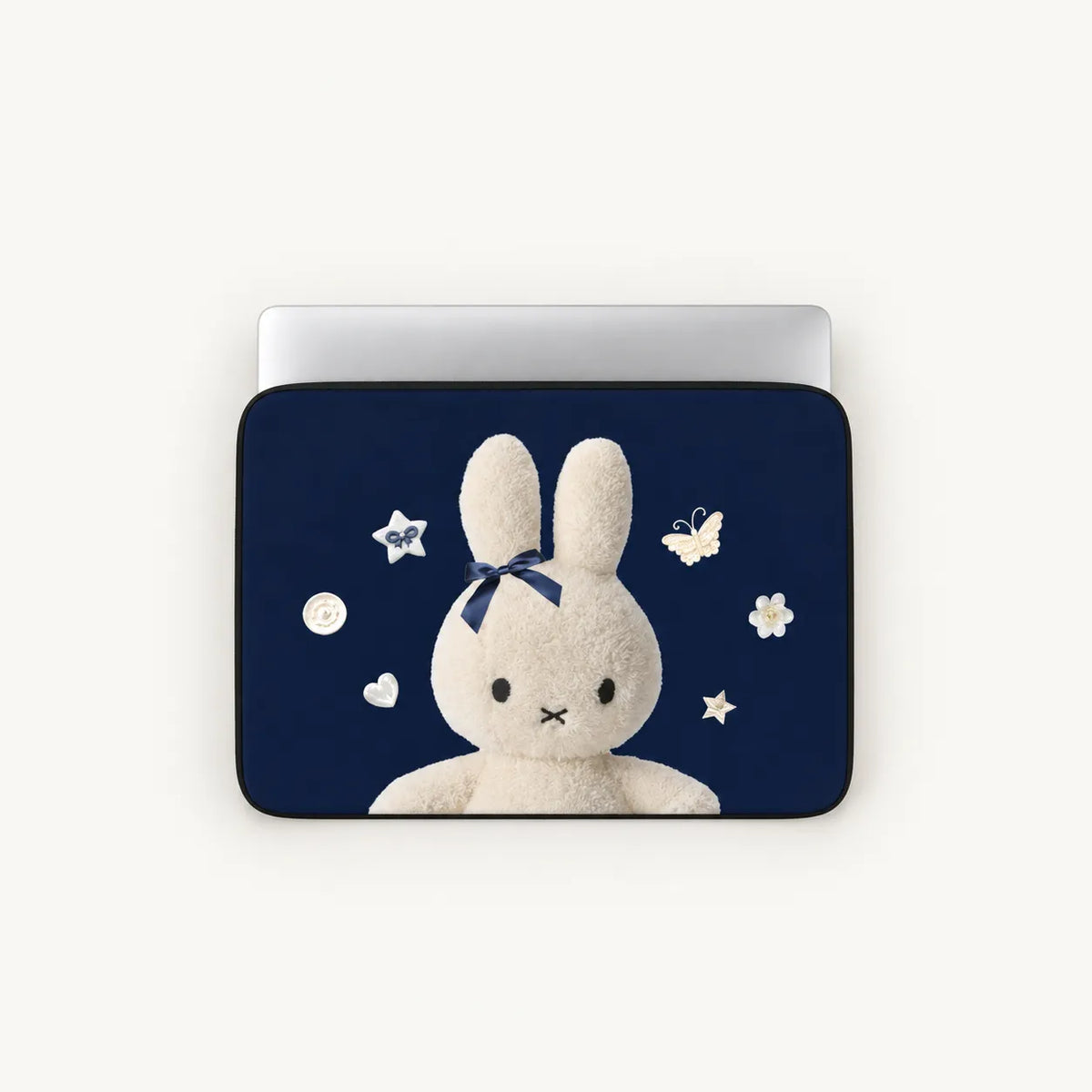 A laptop sleeve featuring a navy blue background with a white plush bunny wearing a dark blue bow, surrounded by small white stars, flowers, and butterflies. The sleeve is shown on a silver laptop against a light off-white background.
