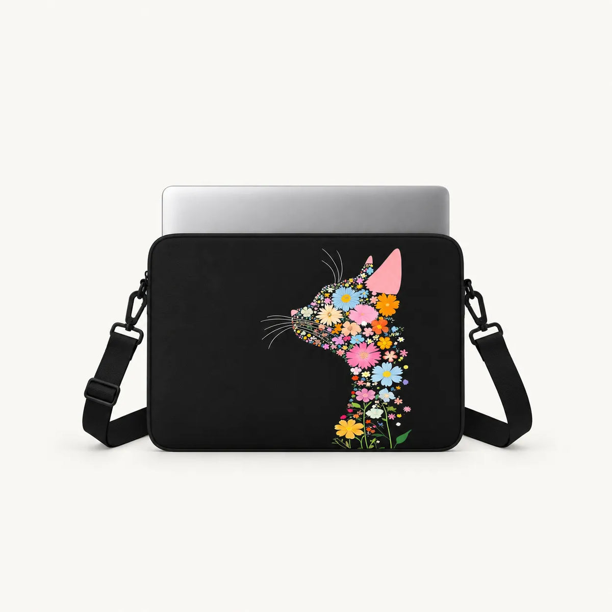 A black laptop sleeve with a colorful floral cat silhouette design, shown with a silver laptop inserted and a black shoulder strap against a light gray background.