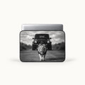 Powerful male lion walking on a road in front of a Mercedes G-Wagon car in dramatic black and white print on a padded laptop sleeve by SLEEVER