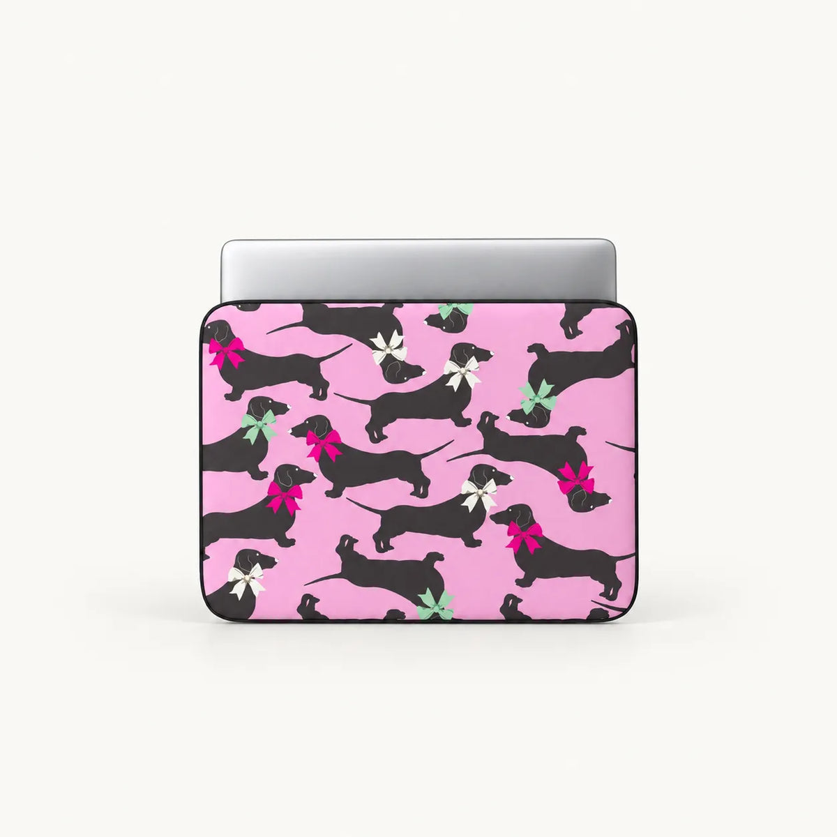 Seamless pattern of black dachshund dogs wearing colorful pink white and green ribbons on a pink padded laptop sleeve by SLEEVER