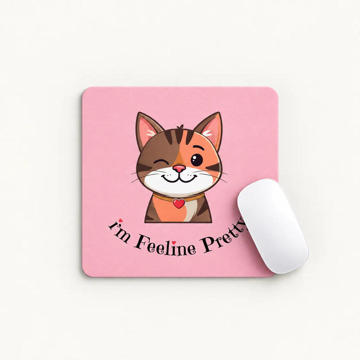 A square pink mouse pad with a cartoon winking orange-and-white cat and the text 'I'm Feeline Pretty' in black script, shown on a light neutral background with a white computer mouse resting on it.