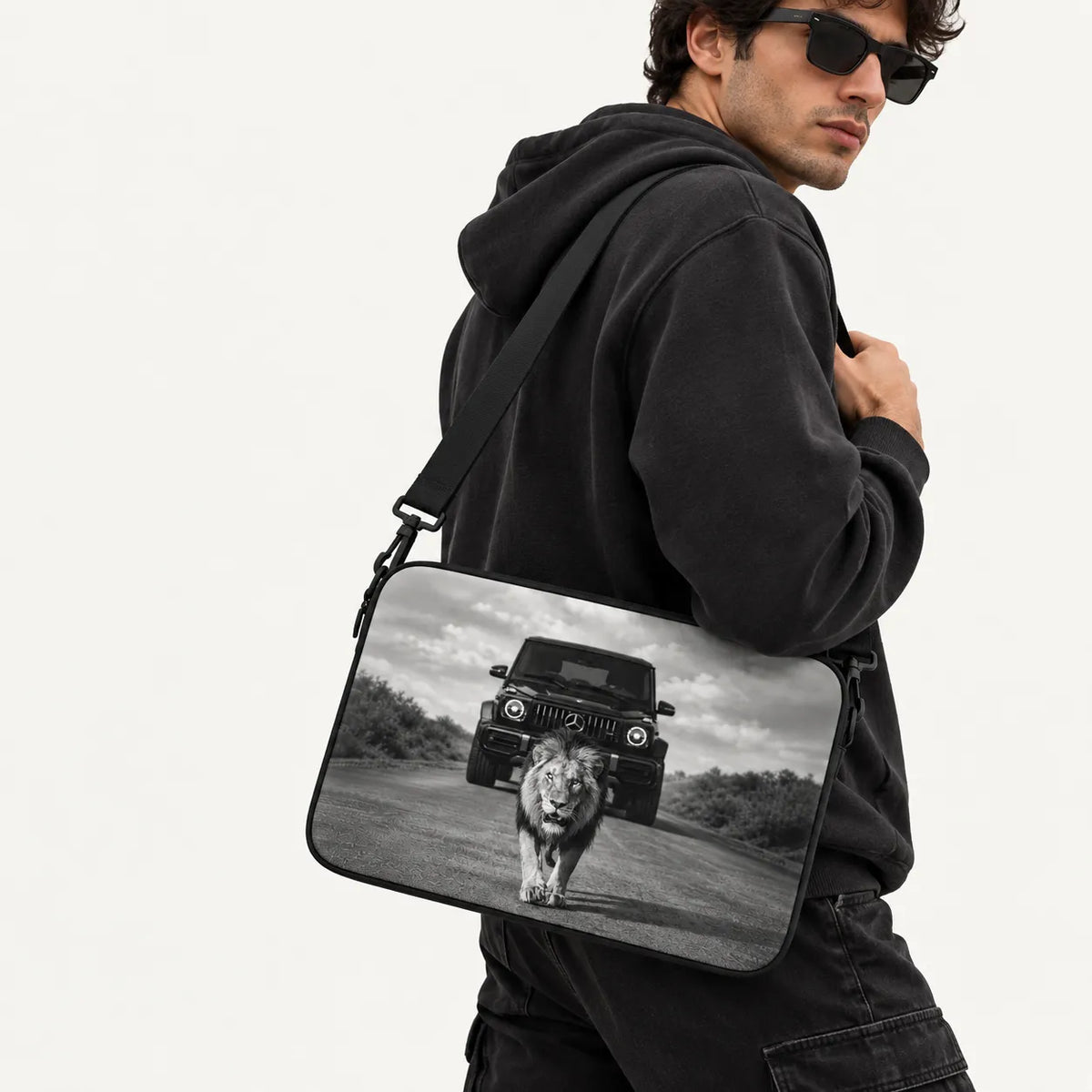 Powerful male lion walking on a road in front of a Mercedes G-Wagon car in dramatic black and white print on a padded laptop sleeve by SLEEVER