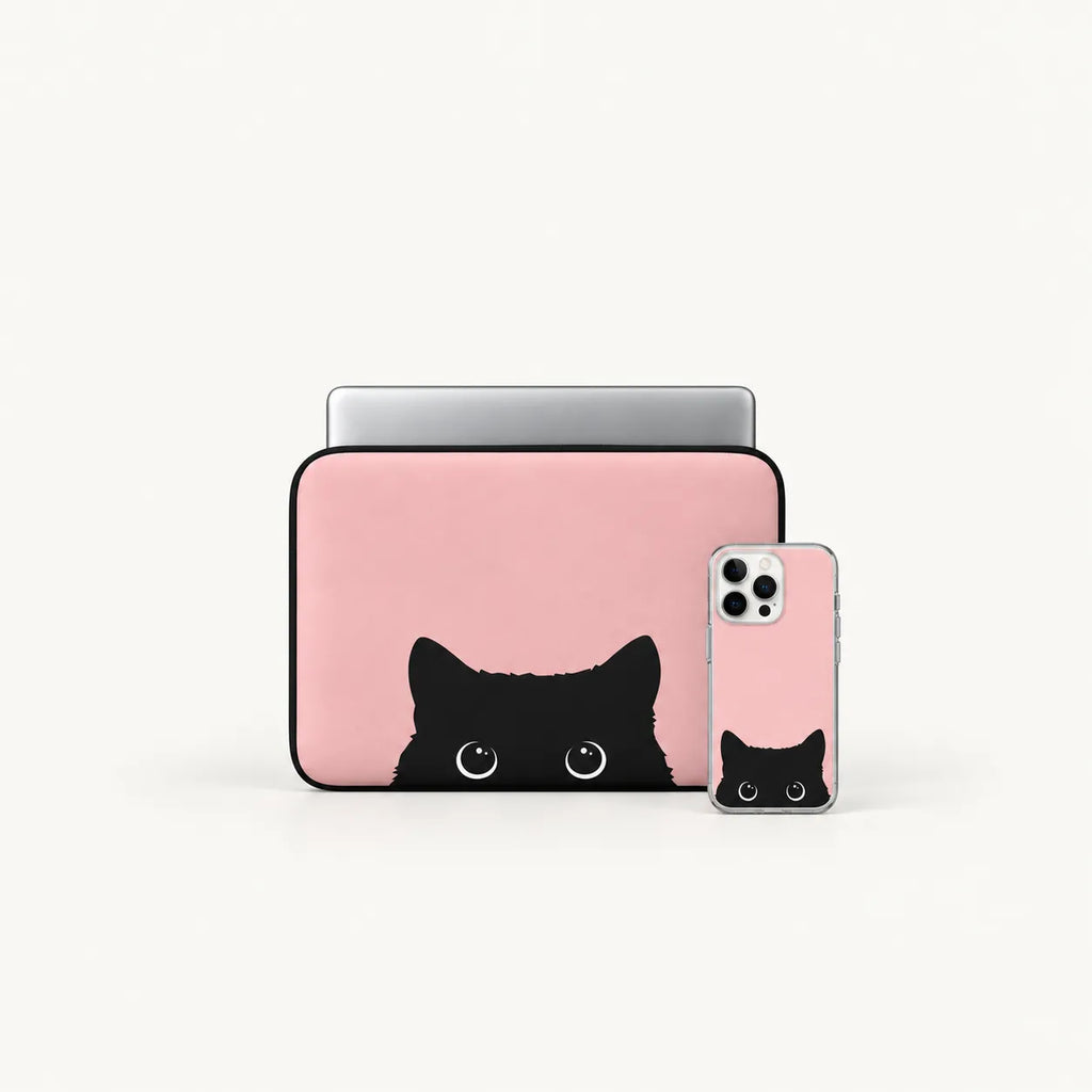A pink laptop sleeve and matching phone case with a black cat face peeking out from the bottom, shown on a clean white background.