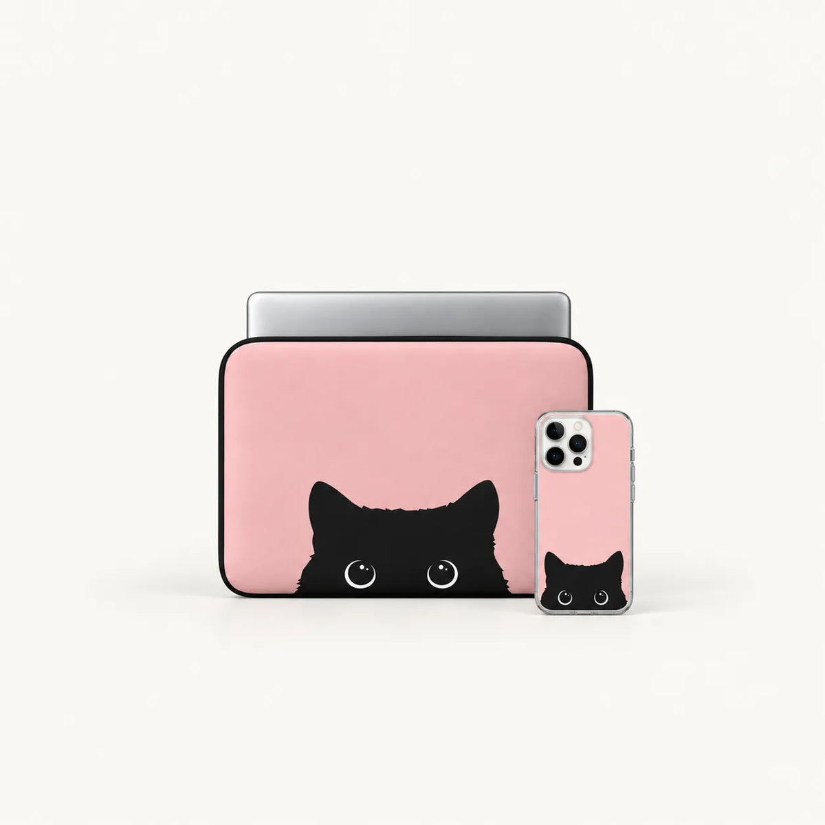 A pink laptop sleeve and matching phone case with a black cat face peeking out from the bottom, shown on a clean white background.