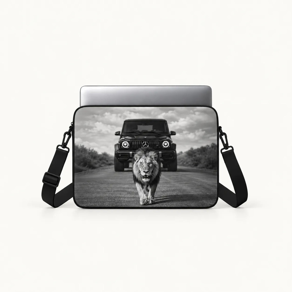 Powerful male lion walking on a road in front of a Mercedes G-Wagon car in dramatic black and white print on a padded laptop sleeve by SLEEVER