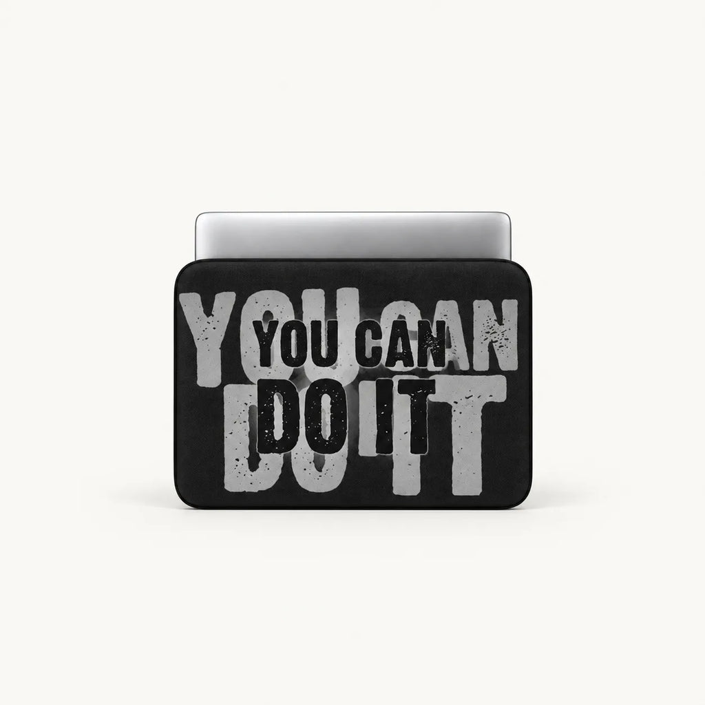 A black laptop sleeve with a motivational graphic reading 'YOU CAN DO IT' in distressed gray and black lettering, shown on a light gray background with a silver laptop partially visible inside.
