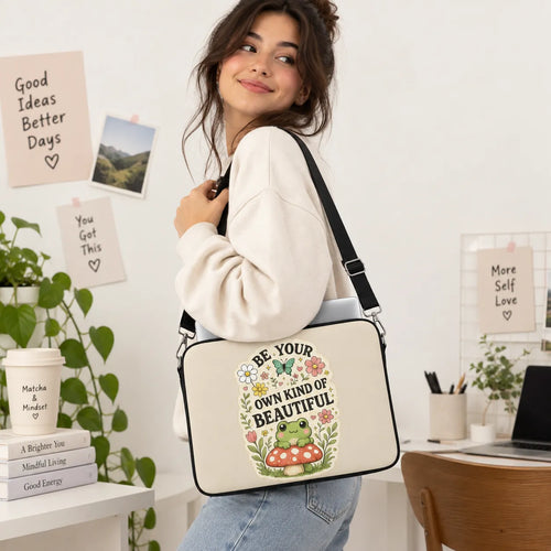 Cute green frog sitting on a red toadstool surrounded by flowers and Be Your Own Kind of Beautiful typography on cream padded laptop sleeve by SLEEVER