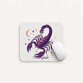 A white rectangular mouse pad with rounded corners featuring a purple scorpion illustration and the word 'Scorpio' beneath it, shown on a light neutral background with a white computer mouse resting on it.