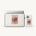 A laptop sleeve and a clear phone case, both printed with the phrase 'TAKE IT EASY' in beige letters over a red floral burst, shown on a light gray background.
