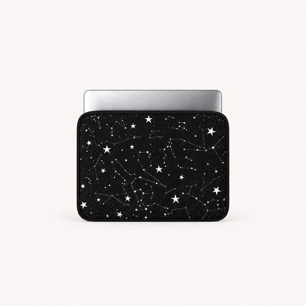 A laptop sleeve featuring a black space design with white stars and constellation patterns, shown with a silver laptop inside on a light gray background.
