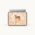 A laptop sleeve featuring a watercolor-style illustration of a fawn surrounded by pink flowers, shown on a silver laptop against a light gray background.