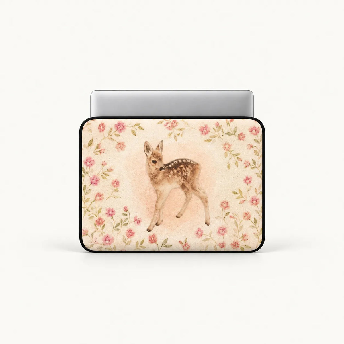A laptop sleeve featuring a watercolor-style illustration of a fawn surrounded by pink flowers, shown on a silver laptop against a light gray background.