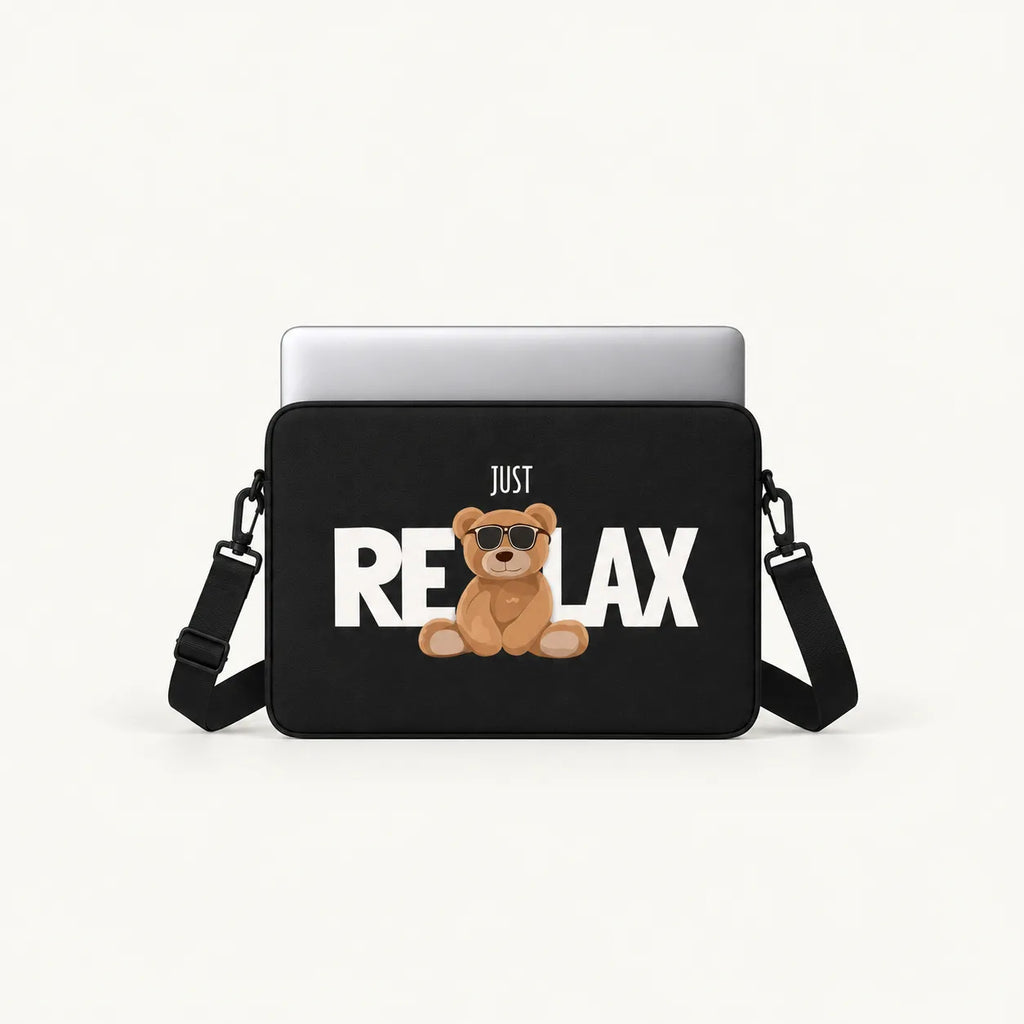 A black laptop sleeve with a printed graphic of a brown teddy bear wearing sunglasses and the text 'JUST RELAX' in white, shown with a silver laptop on a light gray background.