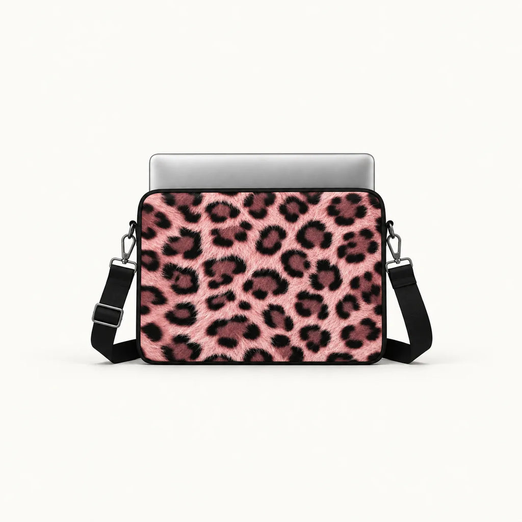 A laptop sleeve featuring a pink and black leopard print pattern, shown with a silver laptop inside and a black shoulder strap on a clean white background.