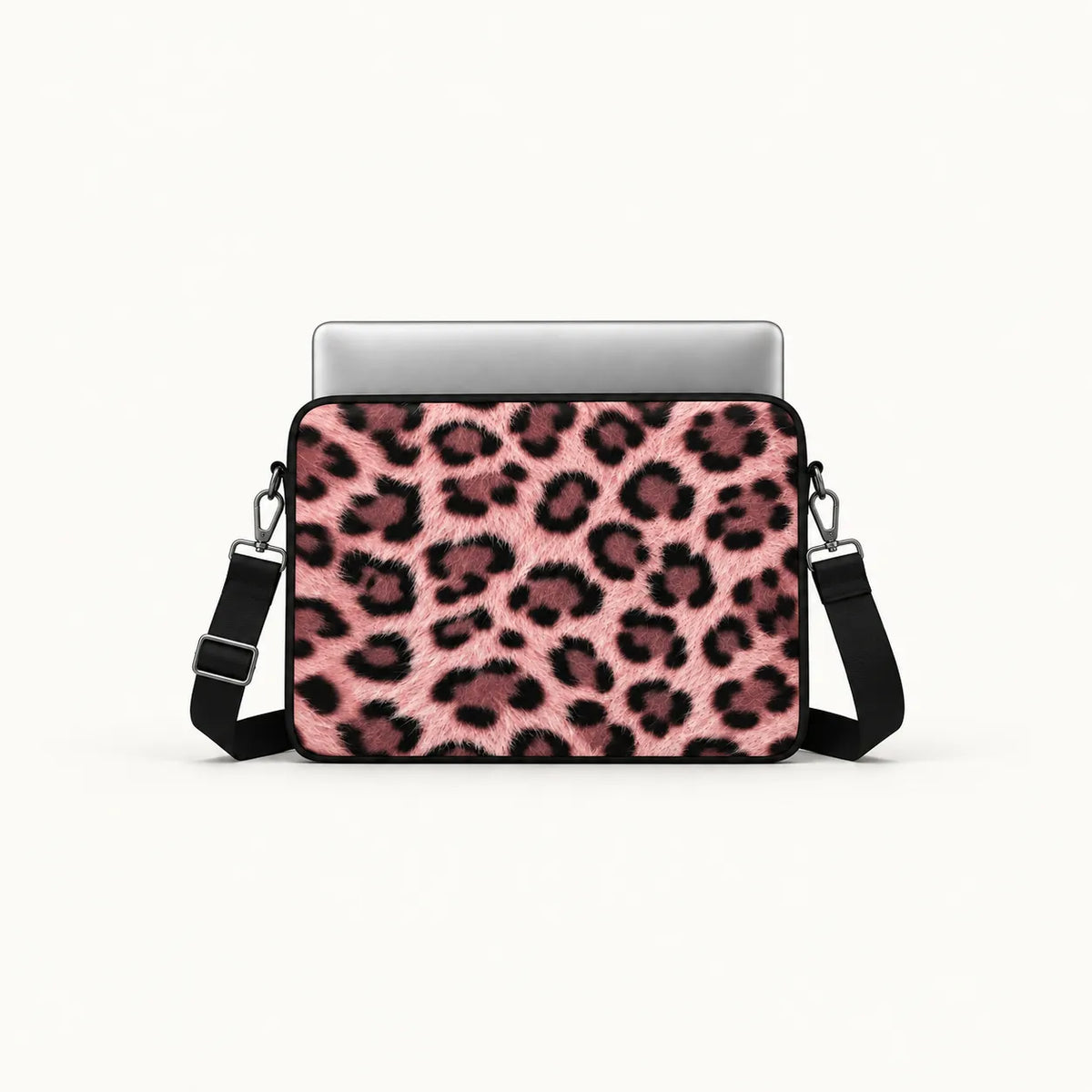 A laptop sleeve featuring a pink and black leopard print pattern, shown with a silver laptop inside and a black shoulder strap on a clean white background.