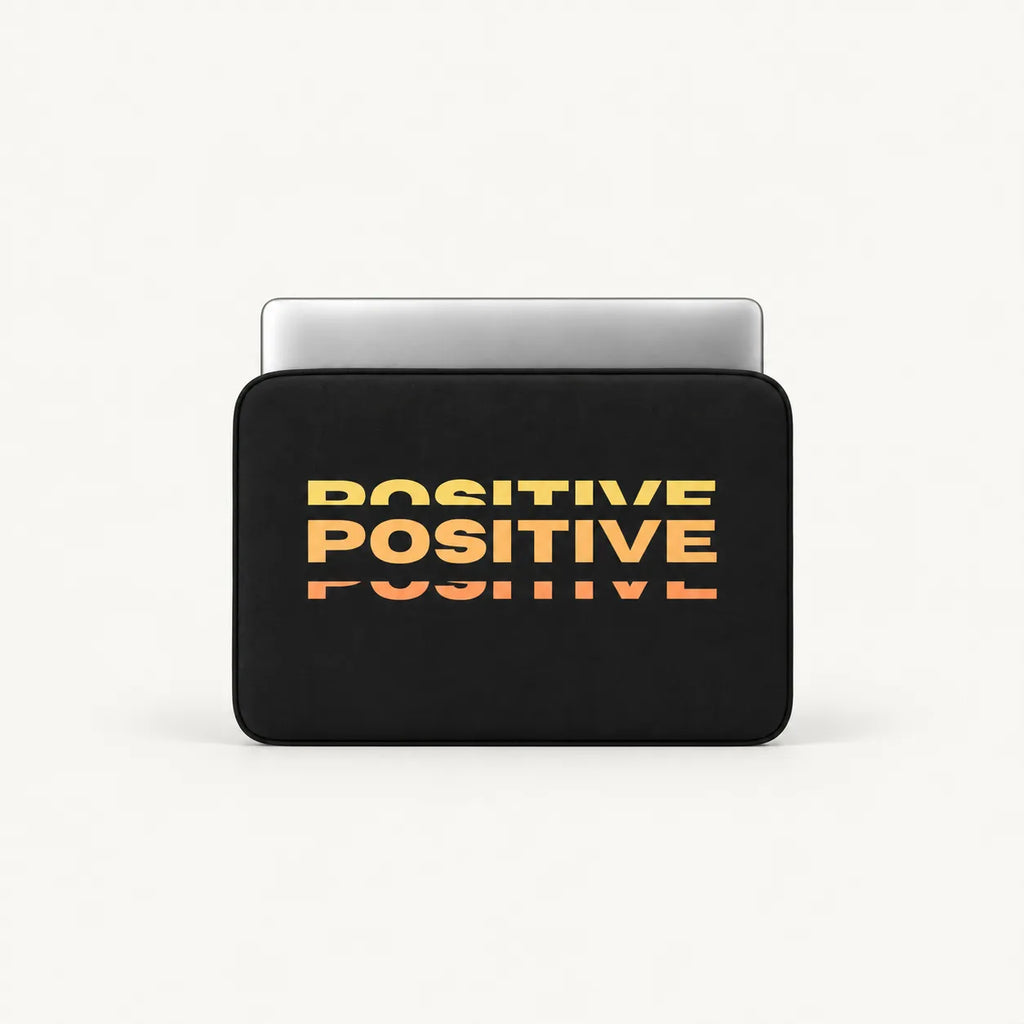 Repeated stacked POSITIVE typography in warm yellow orange sunset gradient effect on a black padded laptop sleeve by SLEEVER