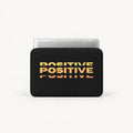 Repeated stacked POSITIVE typography in warm yellow orange sunset gradient effect on a black padded laptop sleeve by SLEEVER