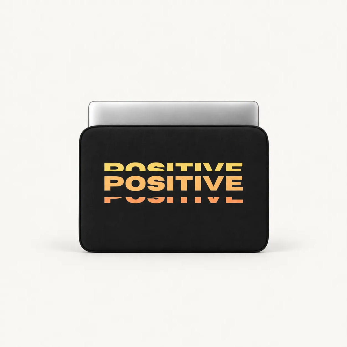 Repeated stacked POSITIVE typography in warm yellow orange sunset gradient effect on a black padded laptop sleeve by SLEEVER