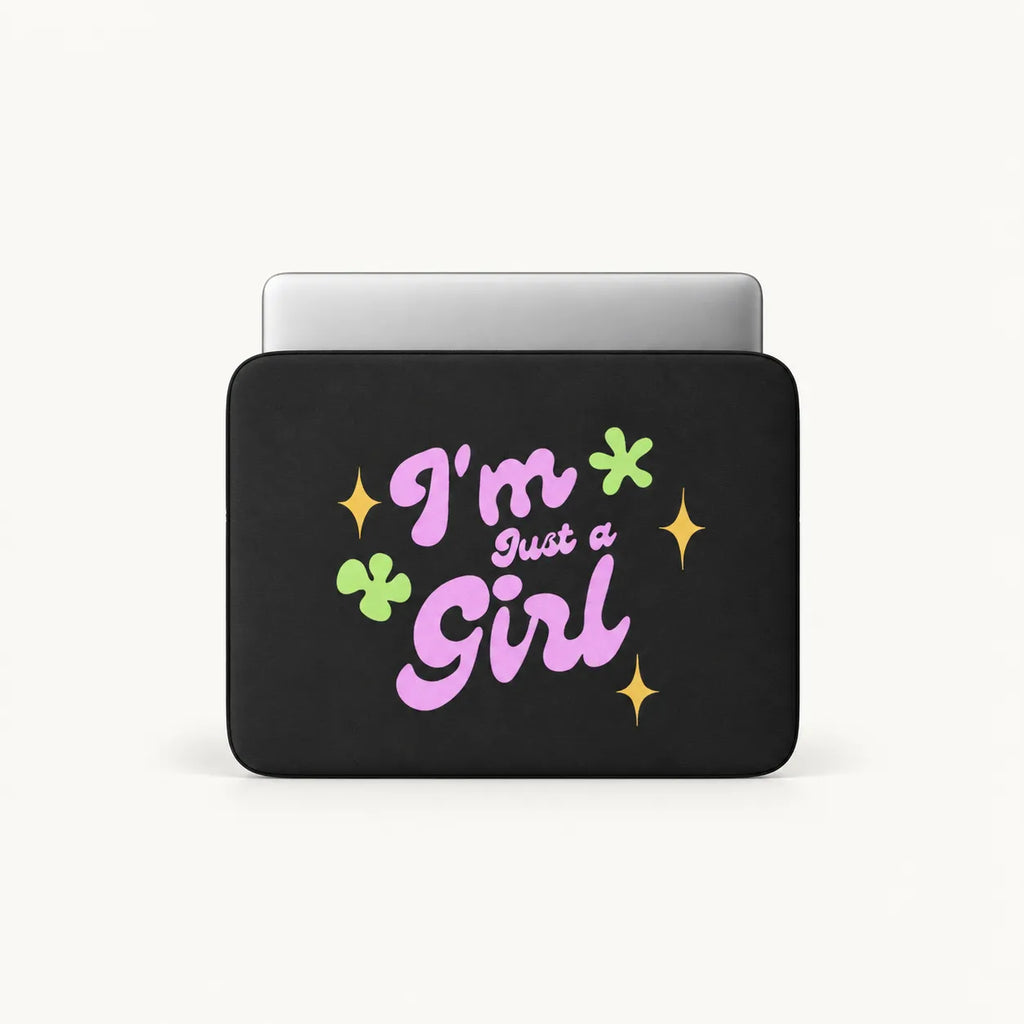 A black laptop sleeve featuring the text 'I'm Just a Girl' in pink and purple lettering, decorated with green clovers and yellow stars, shown on a light gray background.