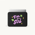 A black laptop sleeve featuring the text 'I'm Just a Girl' in pink and purple lettering, decorated with green clovers and yellow stars, shown on a light gray background.