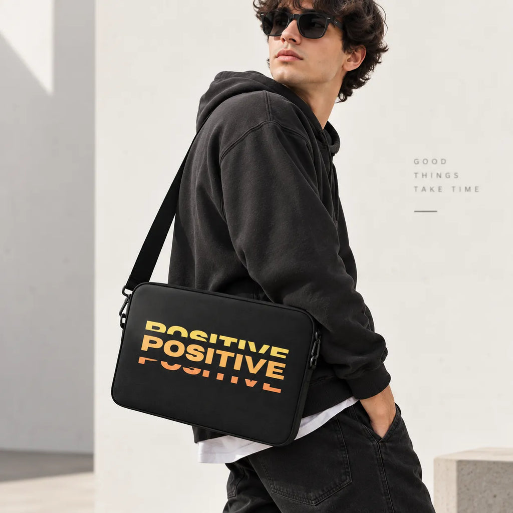Repeated stacked POSITIVE typography in warm yellow orange sunset gradient effect on a black padded laptop sleeve by SLEEVER
